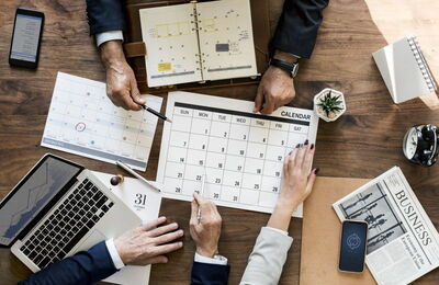 Menschen planen mit Kalender und Laptop