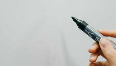 Hand hält einen Stift auf